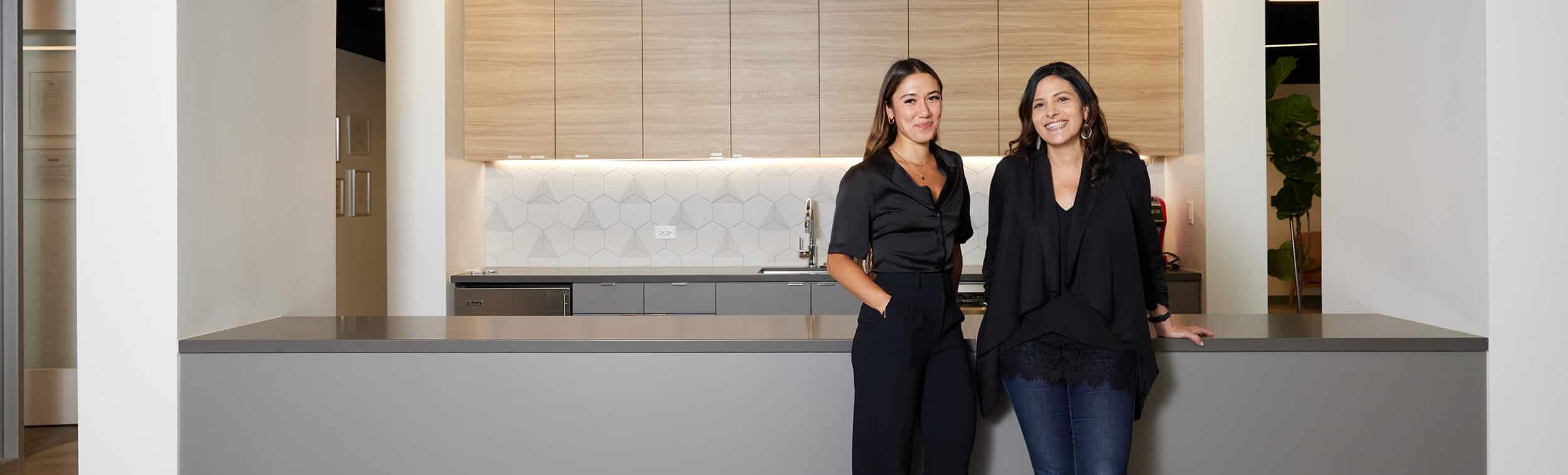 Photo of two Cala colleagues, standing by kitchen counter and smiling